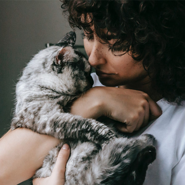woman hugging and looking at cat